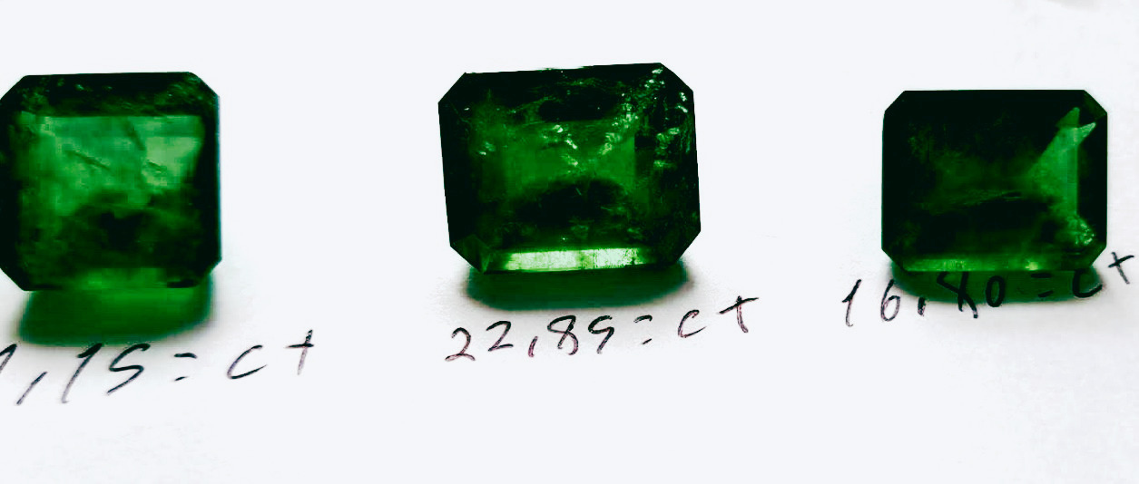 Three cut emeralds on a work surface